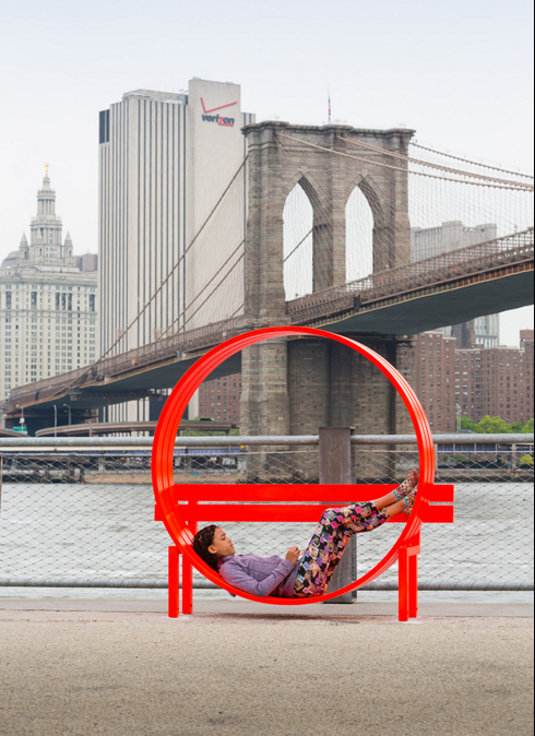 A person rests in an art installation next to the Brooklyn Bridge.