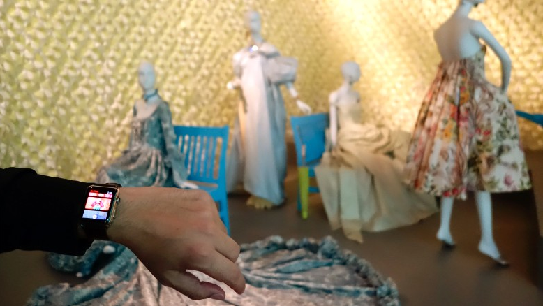 A visitor holds up an Apple Watch at the Oscar de la Renta retrospective at the de Young Museum.