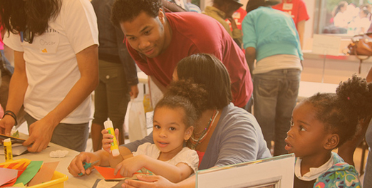 A man helps a young student with an art project.