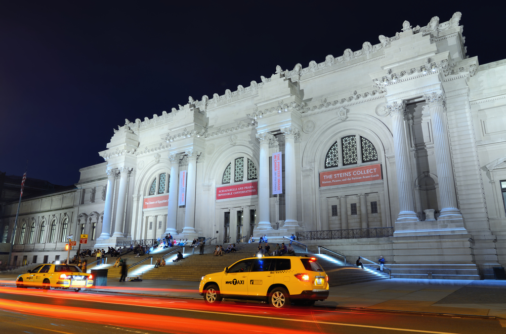 A photograph of the Metropolitan Museum of Art taken at night. The museum is located in New York, NY.