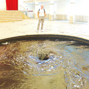 A photo of Anish Kapoor's "Descension." It is a jet black whirlpool in the middle of the ground.