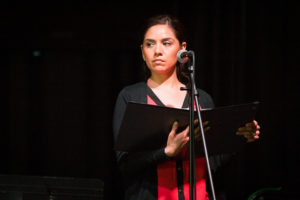 A woman standing in front of a microphone on stage.